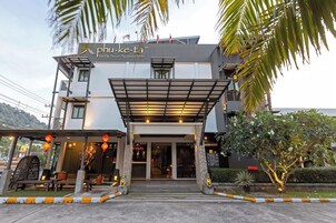 A modern hotel entrance with a covered entrance, stone pillars, and a sign reading "phu-ke-ta The Hip Service Apartment & Hotel".