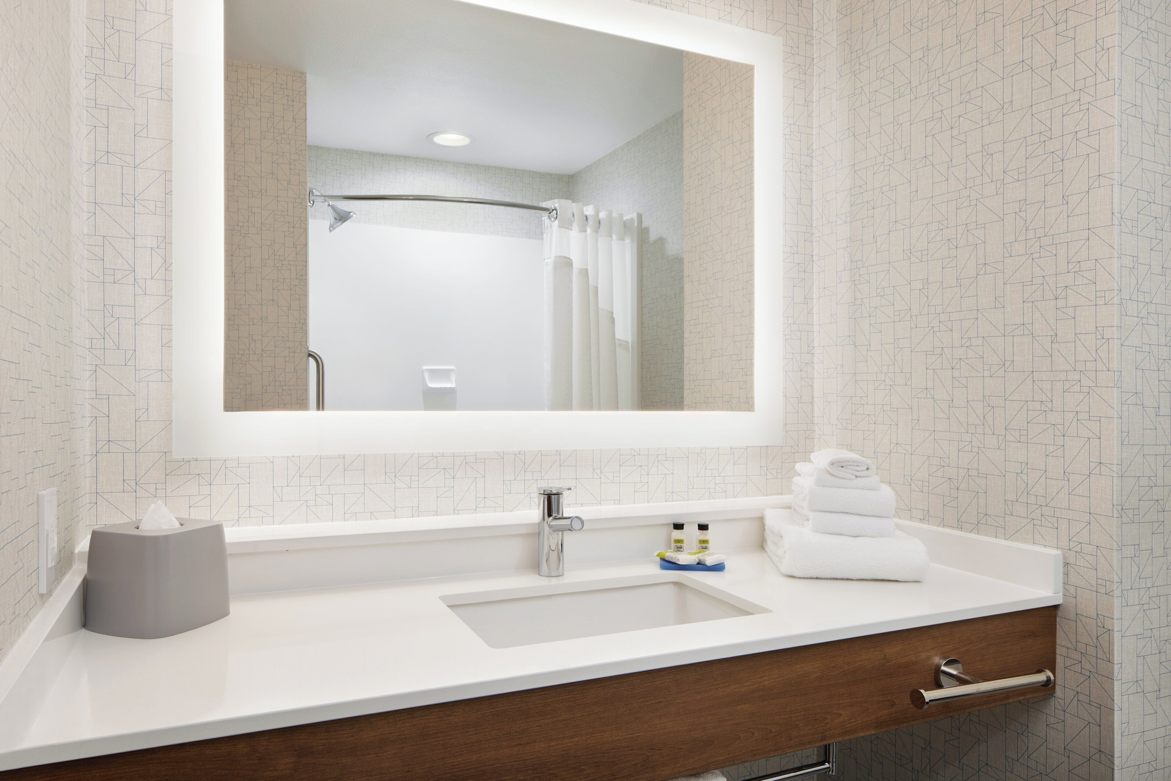 A bathroom with a white sink, a mirror, a towel rack, and a shower curtain.