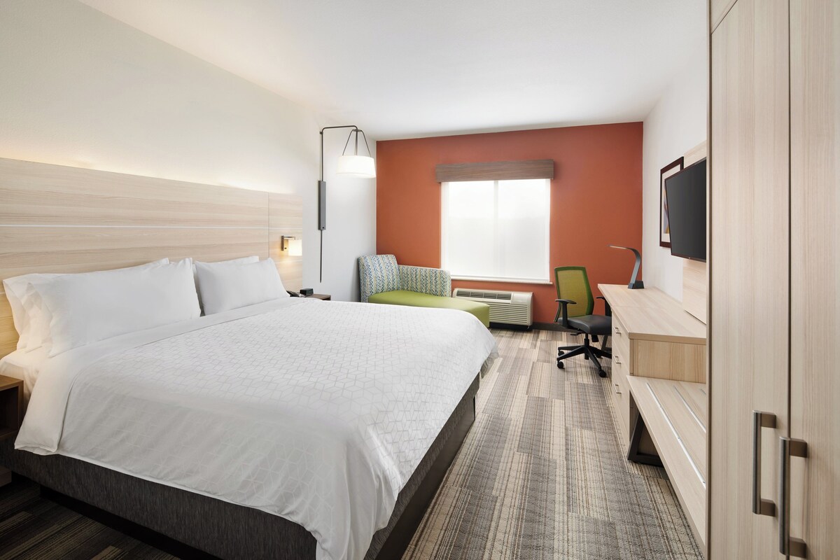 Ein Hotelzimmer mit Bett, Schreibtisch, Stuhl, Fernseher und Fenster.