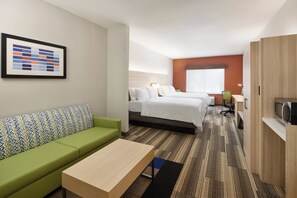Ein Hotelzimmer mit einem grünen Sofa, einem Bett, einem Schreibtisch und einem Fernseher.