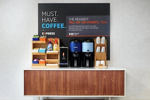 A coffee station with a sign promoting IHG Rewards Club, coffee machines, and a variety of coffee products.