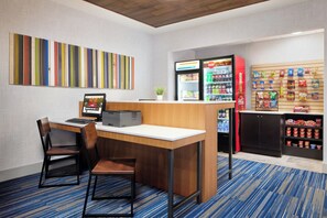 Une chambre d’hôtel équipée d’un bureau, de chaises, d’un distributeur automatique et d’un bar servant des collations.