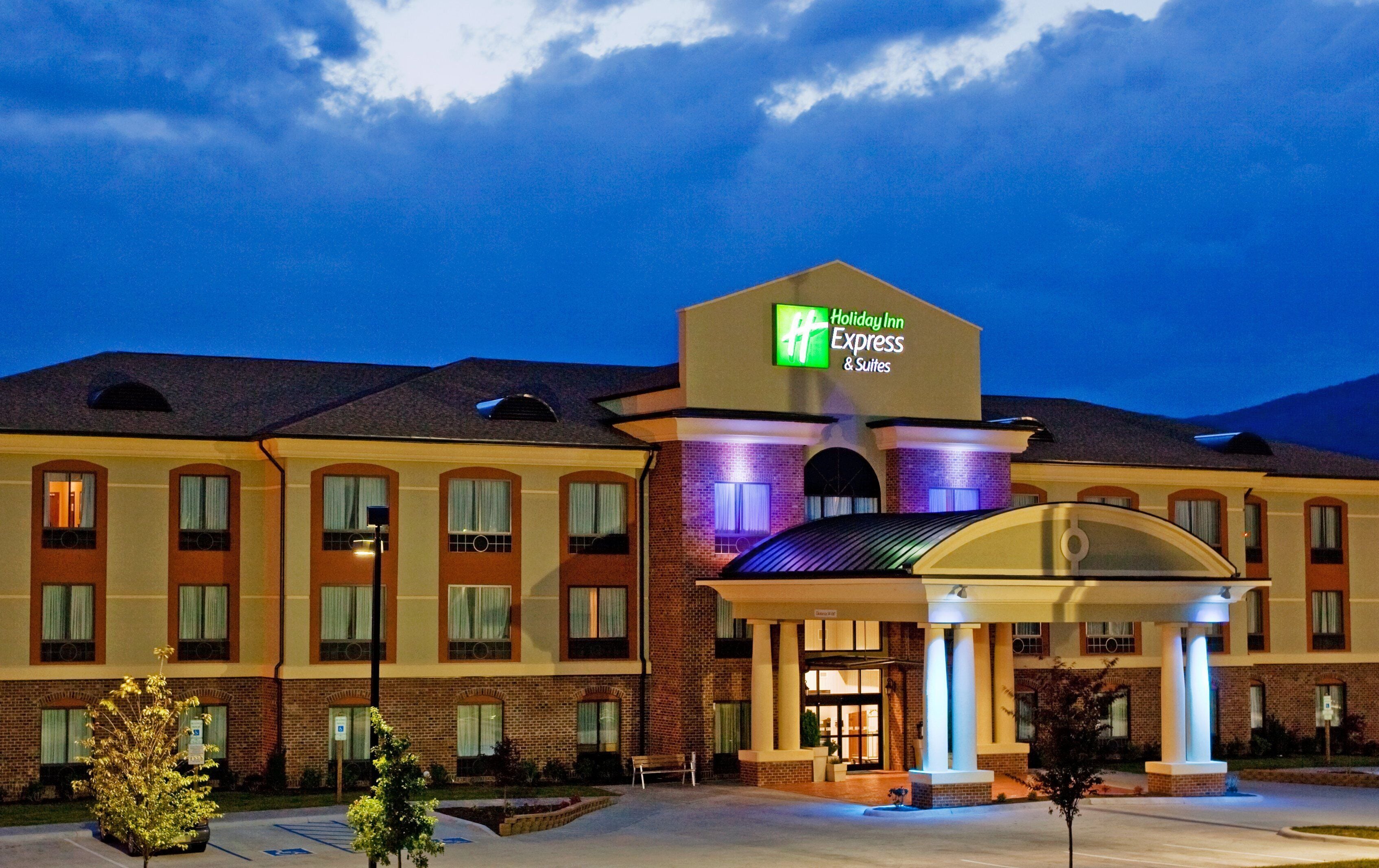 Un hotel Holiday Inn Express con fachada de ladrillo, entrada cubierta y estacionamiento.