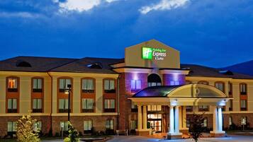 Un hotel Holiday Inn Express con fachada de ladrillo, entrada cubierta y estacionamiento.