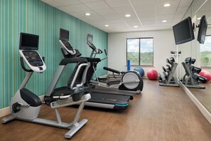 A gym with treadmills, elliptical machines, and exercise balls.