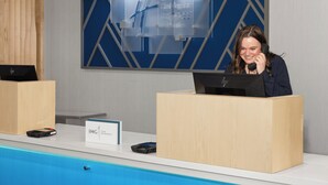 A hotel reception desk with a digital display and a sign indicating a loyalty program. - Holiday Inn Express Hotel & Suites Hamburg by IHG (Hamburg)