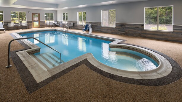 An indoor swimming pool with a clear water edge, a pool ladder, and a seating area with chairs and a table. - Holiday Inn Express Hotel & Suites Hamburg by IHG (Hamburg)
