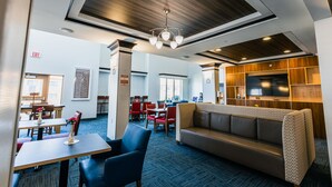 A modern hotel lobby with a seating area, a television, and a patterned wall. - Holiday Inn Express Hotel & Suites Hamburg by IHG (Hamburg)