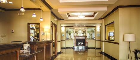 Un hall de hotel con mostrador de recepción, área de registro y una chimenea, además de un espejo.