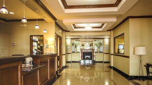 A hotel lobby with a reception desk, a check-in counter, a fireplace, and a mirror. - Holiday Inn Express & Suites Waller - Prairie View by IHG (Waller)