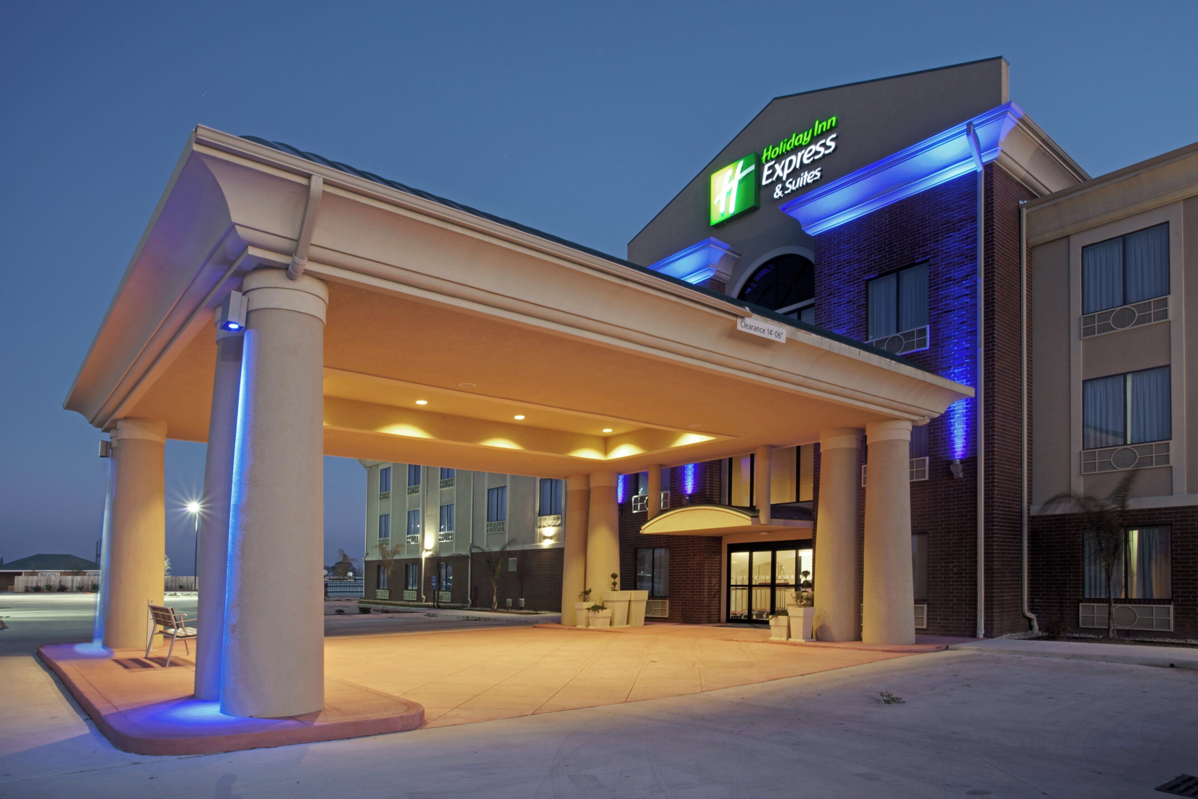 Ein Holiday Inn Express & Suites Hotel mit überdachtem Außenbereich, Säulen und blauem Himmel.