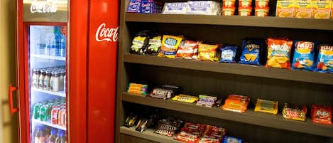 Una máquina expendedora con el logotipo de Coca-Cola y un estante lleno de aperitivos y dulces.
