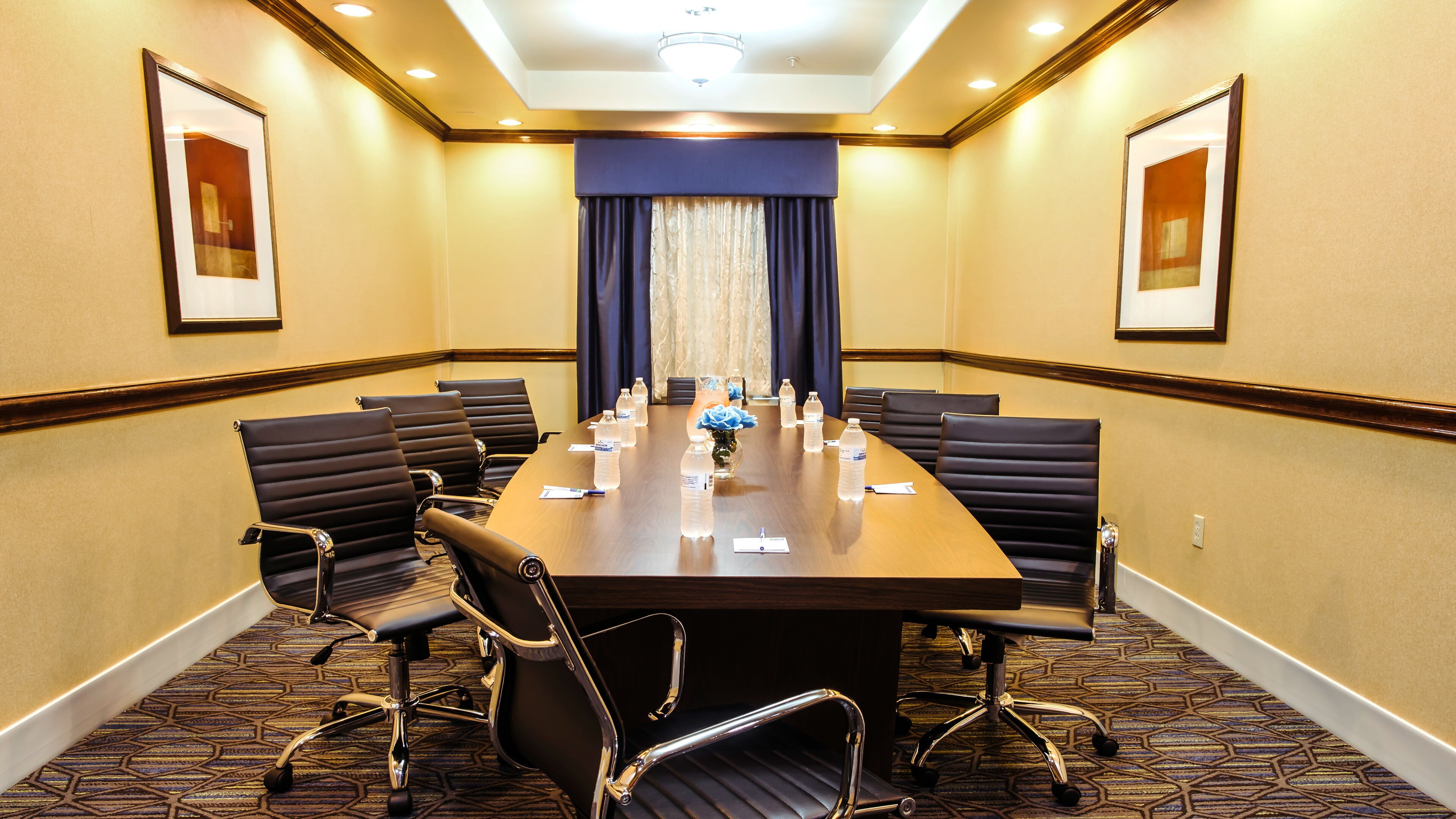 A conference room with a long table, multiple chairs, and water bottles.