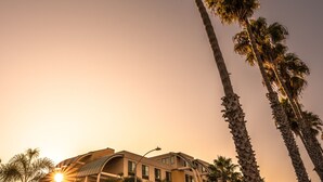 A hotel with a curved roof, palm trees in front, and a sunset in the background. - Holiday Inn Oceanside Camp Pendleton Area by IHG (Oceanside)