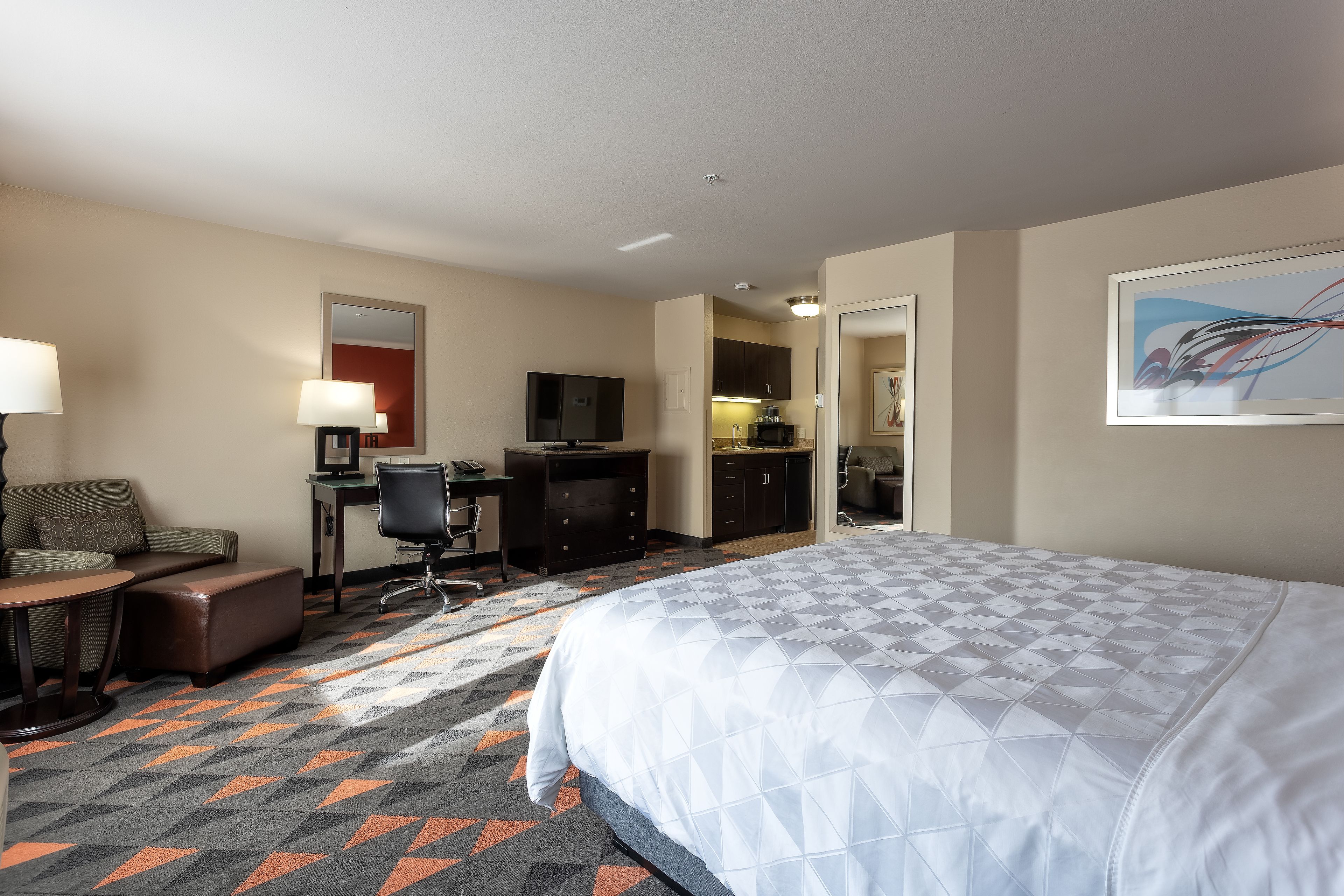 Een hotelkamer met een groot bed, een bureau met een computer, een stoel en een televisie.
