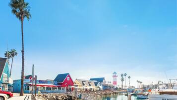 A marina with boats docked, a red building, and palm trees.