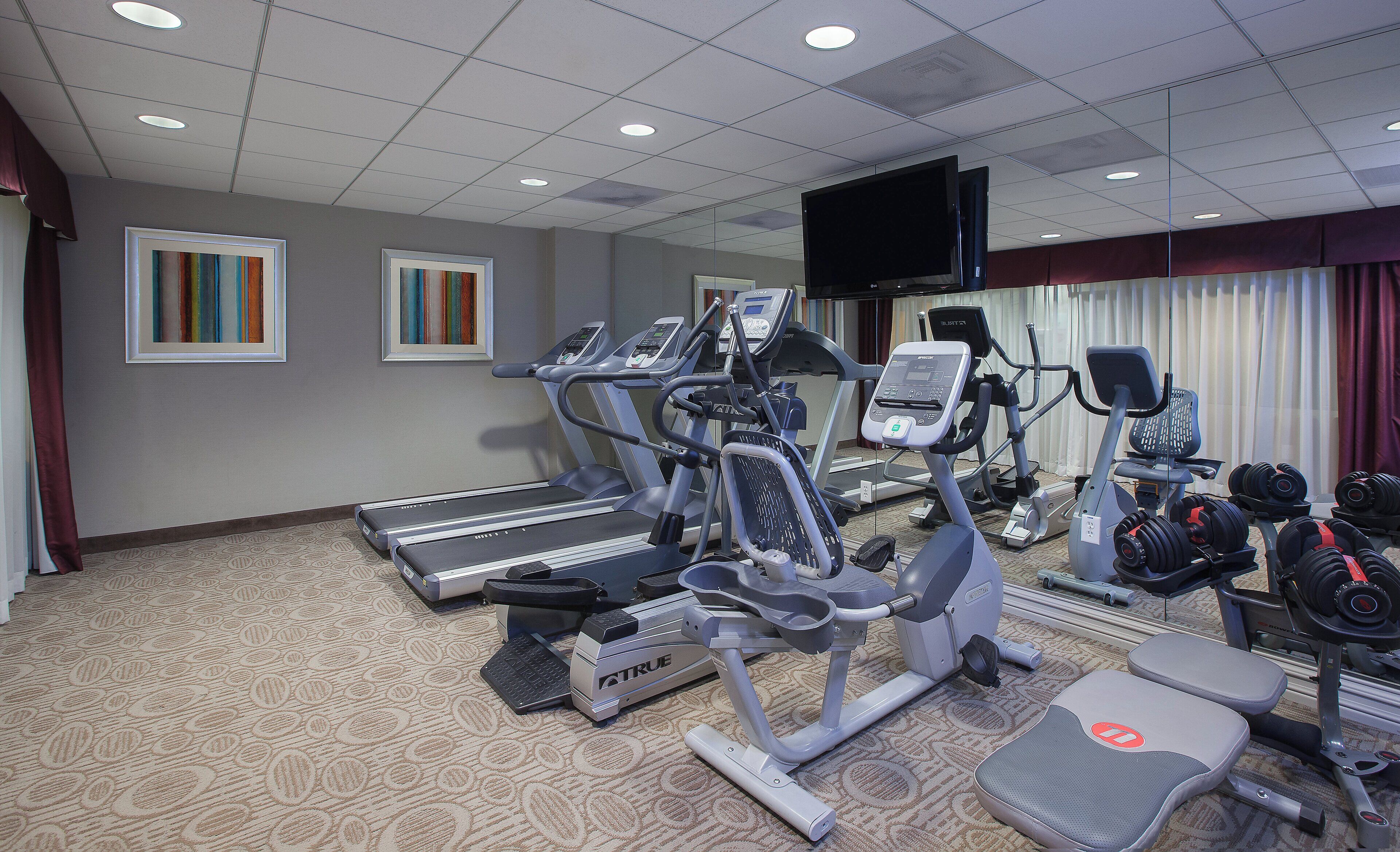 Een fitnessruimte met loopbanden, elliptische trainers en gewichten.