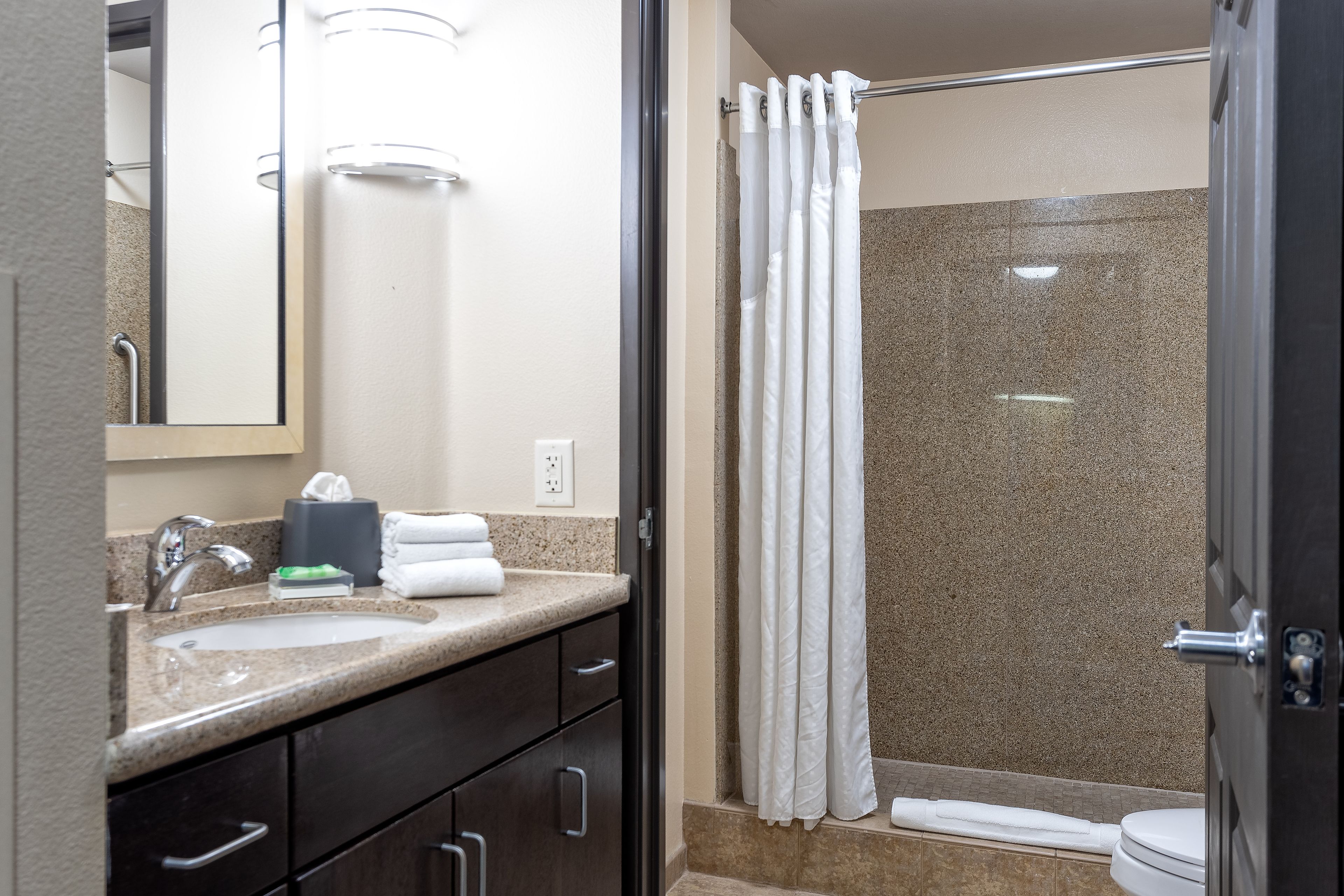 A bathroom with a sink, mirror, towel rack, and shower curtain.