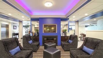 A lobby with a fireplace, seating area, and a reception desk.