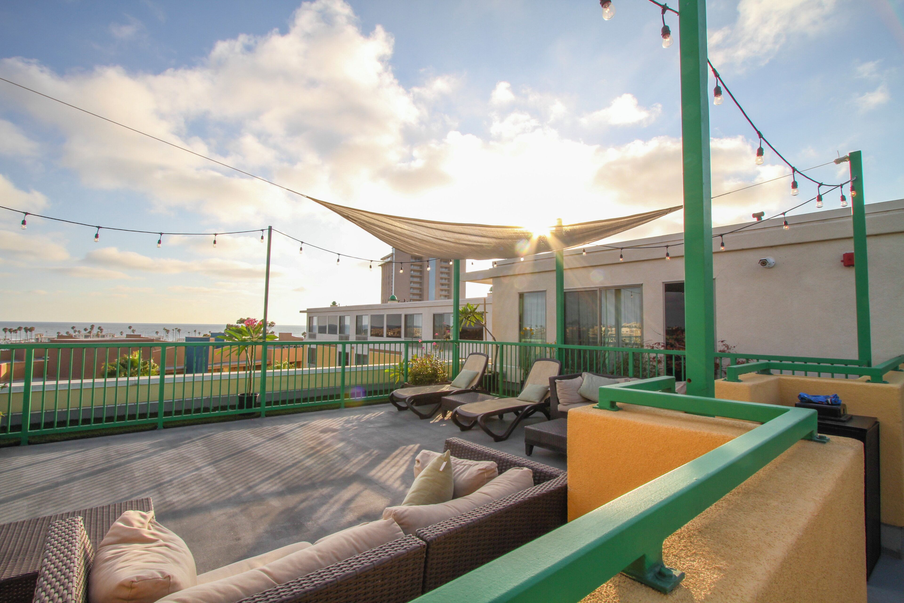 A rooftop terrace with outdoor seating, a view of the sea, and a building in the background.
