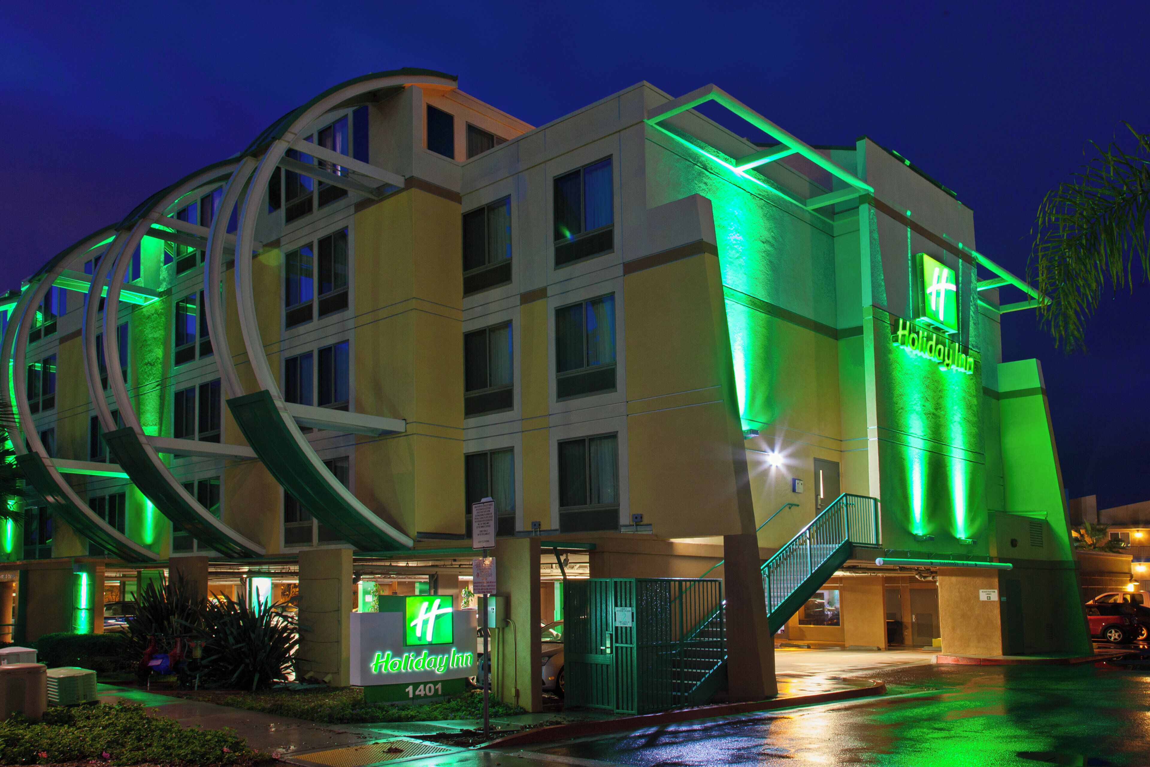 A Holiday Inn hotel with a modern design, featuring a prominent staircase and a neon sign.