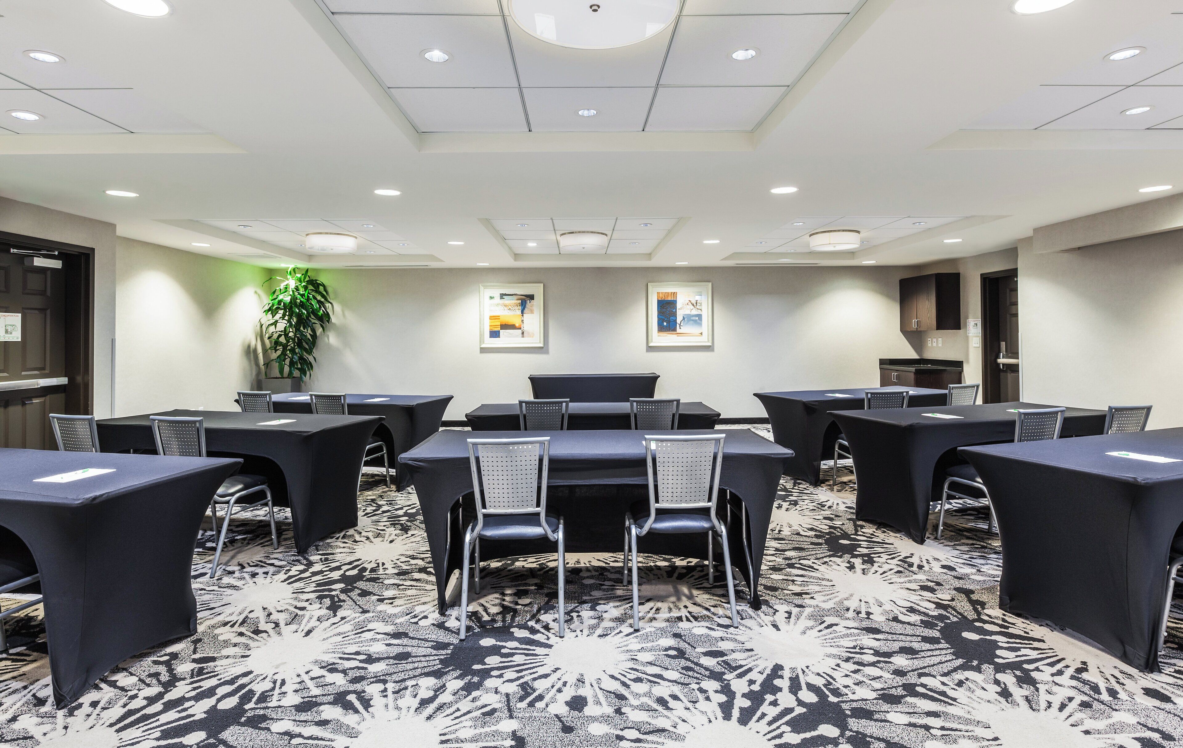 A conference room with tables and chairs, a patterned carpet, and artwork on the walls.