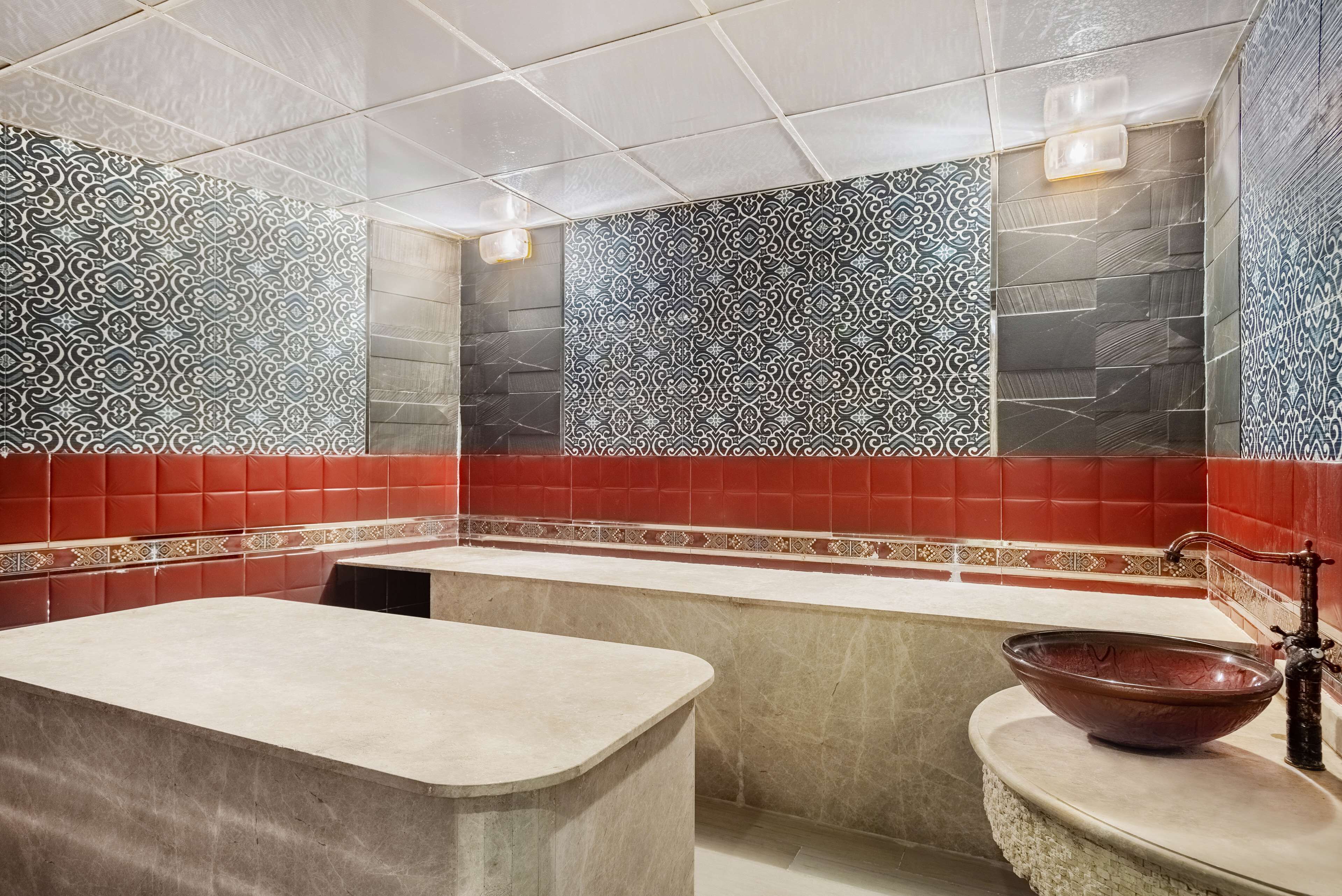 A modern bathroom with a large bathtub, a freestanding sink, and patterned tile walls.
