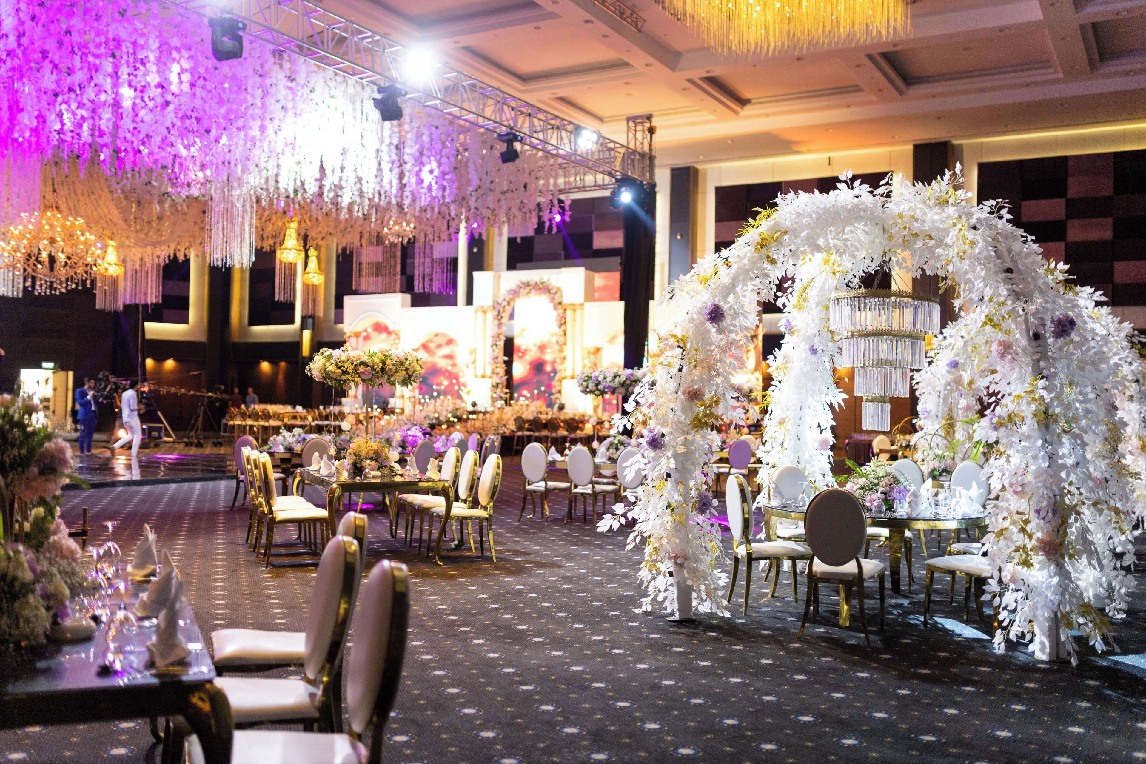A banquet hall with round tables, chairs, and floral decorations.
