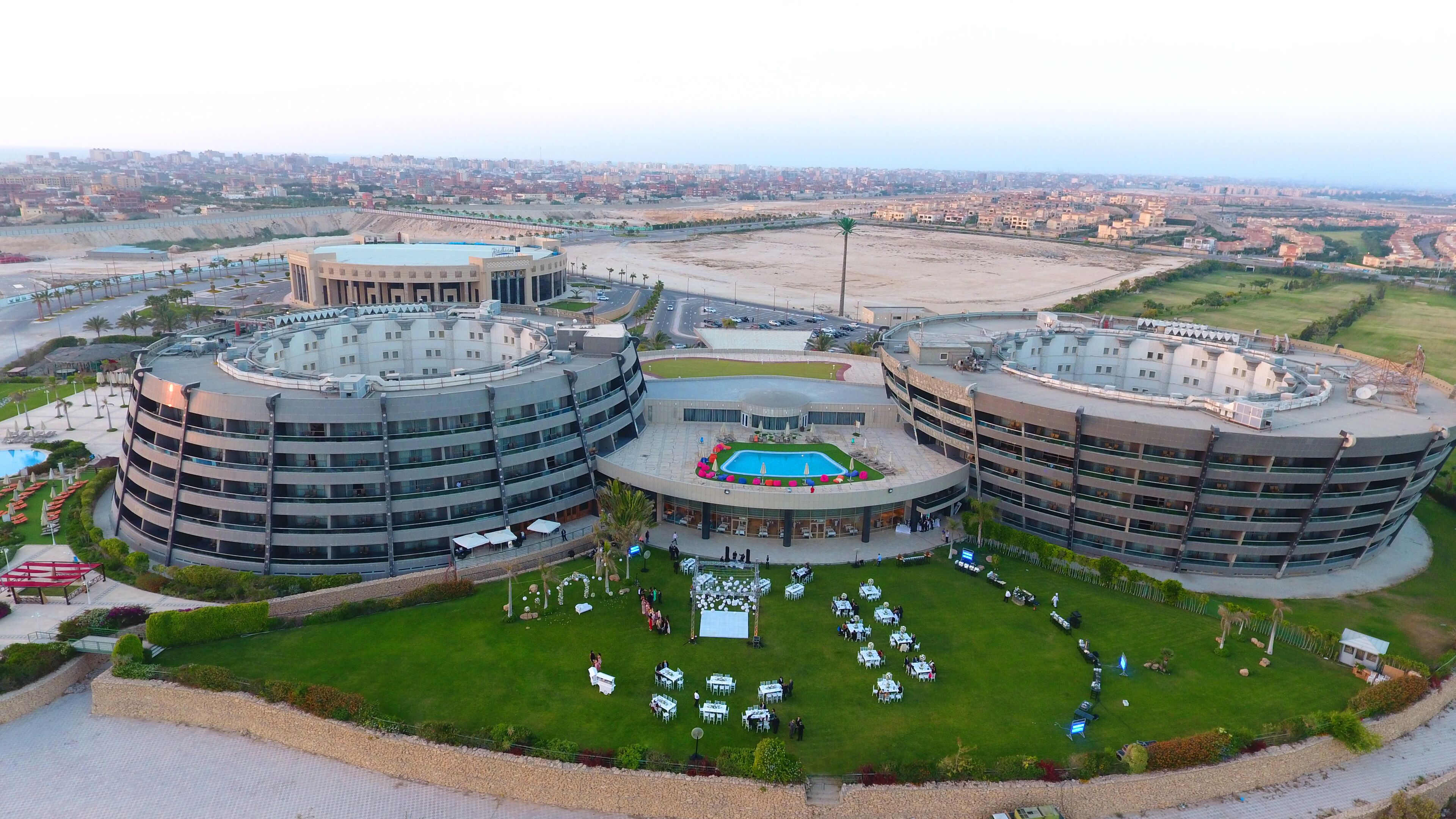 A modern hotel with a central courtyard, multiple floors, and a pool area.