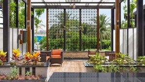 A covered outdoor seating area with wicker furniture and potted plants. - Radisson Blu Hotel & Convention Center, Alexandria (Al-'Amriyah)