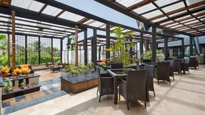 A spacious indoor garden with seating areas, large windows, and potted plants. - Radisson Blu Hotel & Convention Center, Alexandria (Al-'Amriyah)