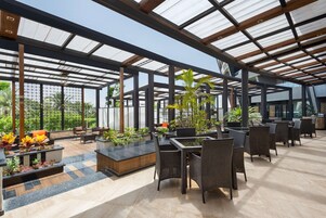 Un jardín interior amplio con zonas de estar, ventanas grandes y plantas en macetas.