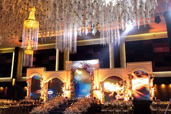 A banquet hall with a stage, chandeliers, and floral decorations. - Radisson Blu Hotel & Convention Center, Alexandria (Al-'Amriyah)