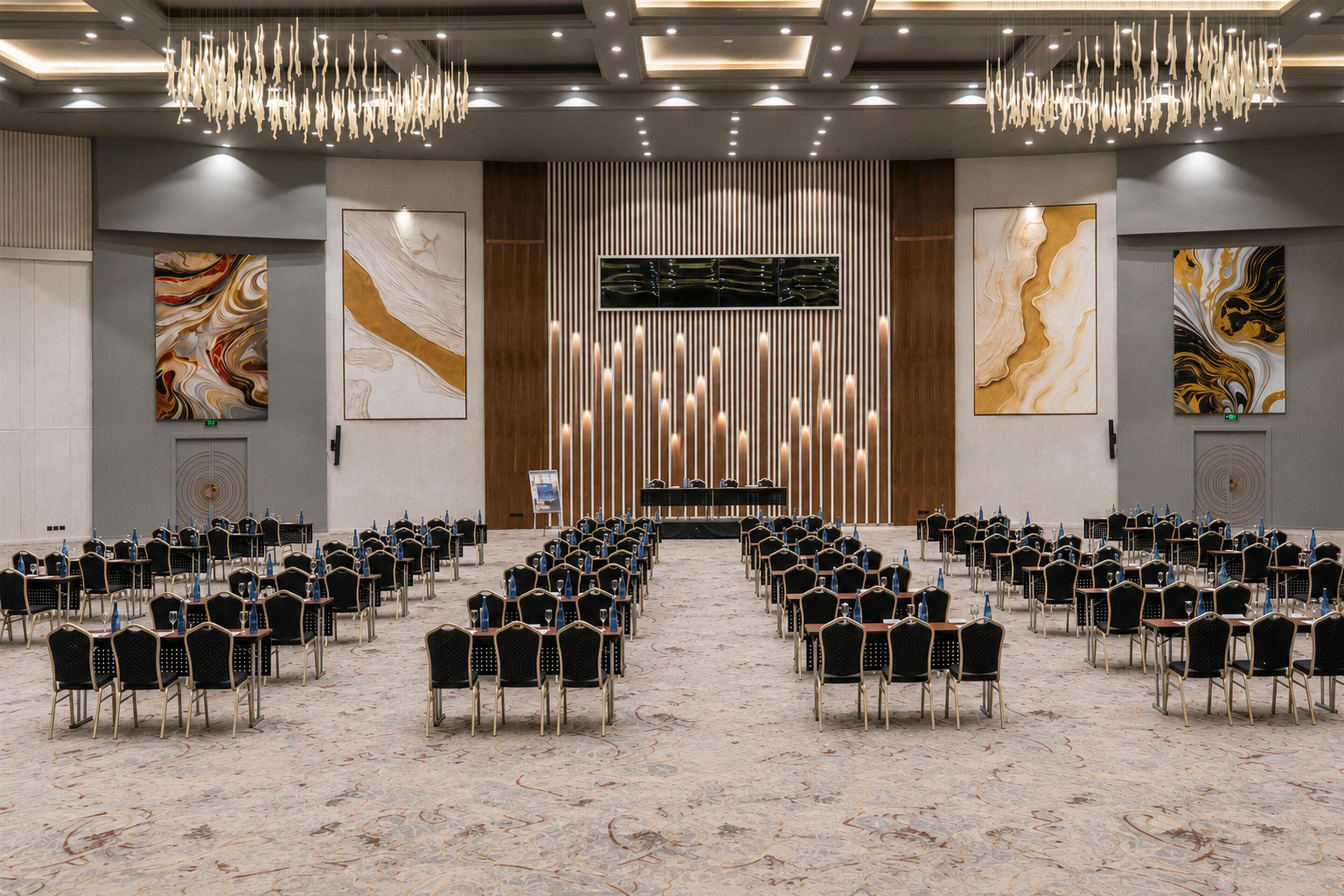 A conference room with rows of chairs, a podium, and abstract art on the walls.