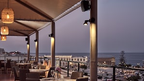 Ein Restaurant mit gedeckten Tischen mit Blick auf Strand und Stadtlandschaft.