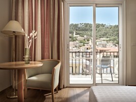 Una camera d'albergo con balcone, un tavolo con lampada, una sedia e un letto.
