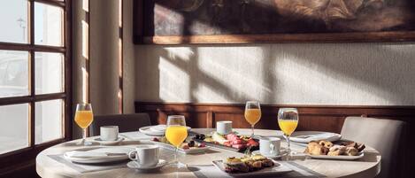 A round dining table with breakfast items, glasses of orange juice, and a painting on the wall.