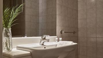 Un baño moderno con un lavamanos grande, espejo y zona de ducha.