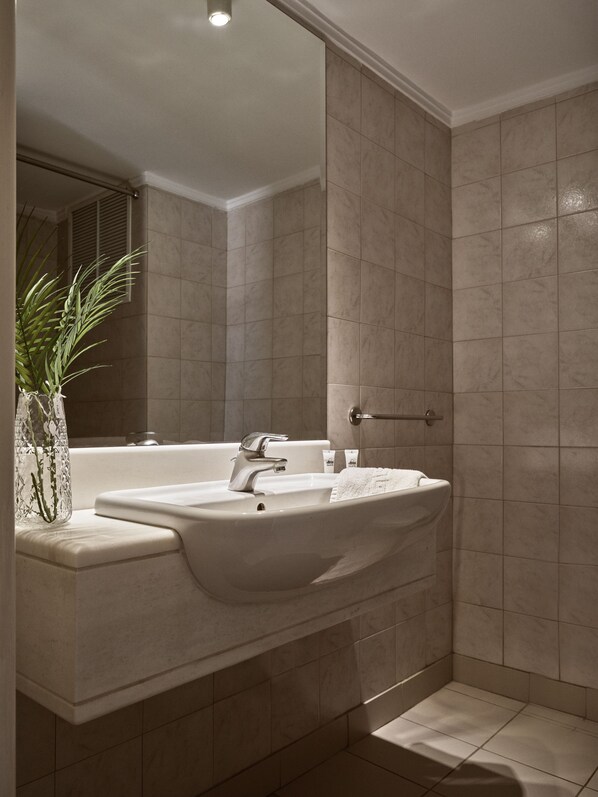 Un baño moderno con un lavamanos grande, espejo y zona de ducha.