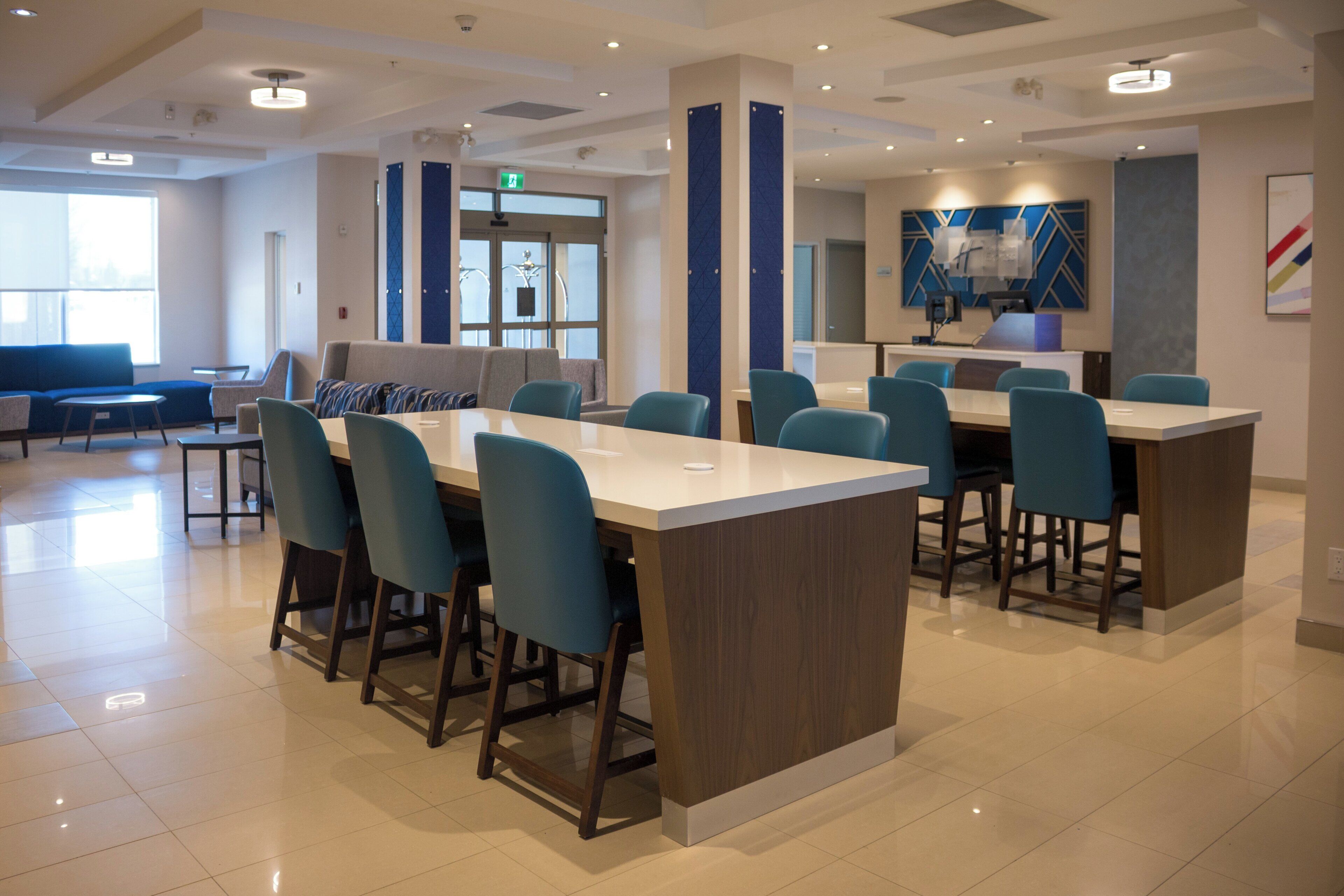 Un hall d’hôtel moderne avec une table centrale, des sièges et un espace d’accueil.