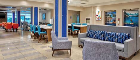 A spacious lobby with a long table, several chairs, a sofa, and a large pillar.
