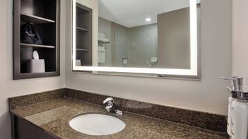 Casa de banho com bancada de granito, lavatório, espelho e porta-toalhas.