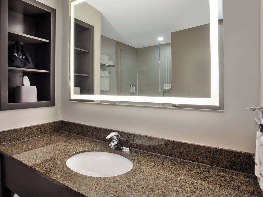 A bathroom with a granite countertop sink, a mirror, and a towel rack.