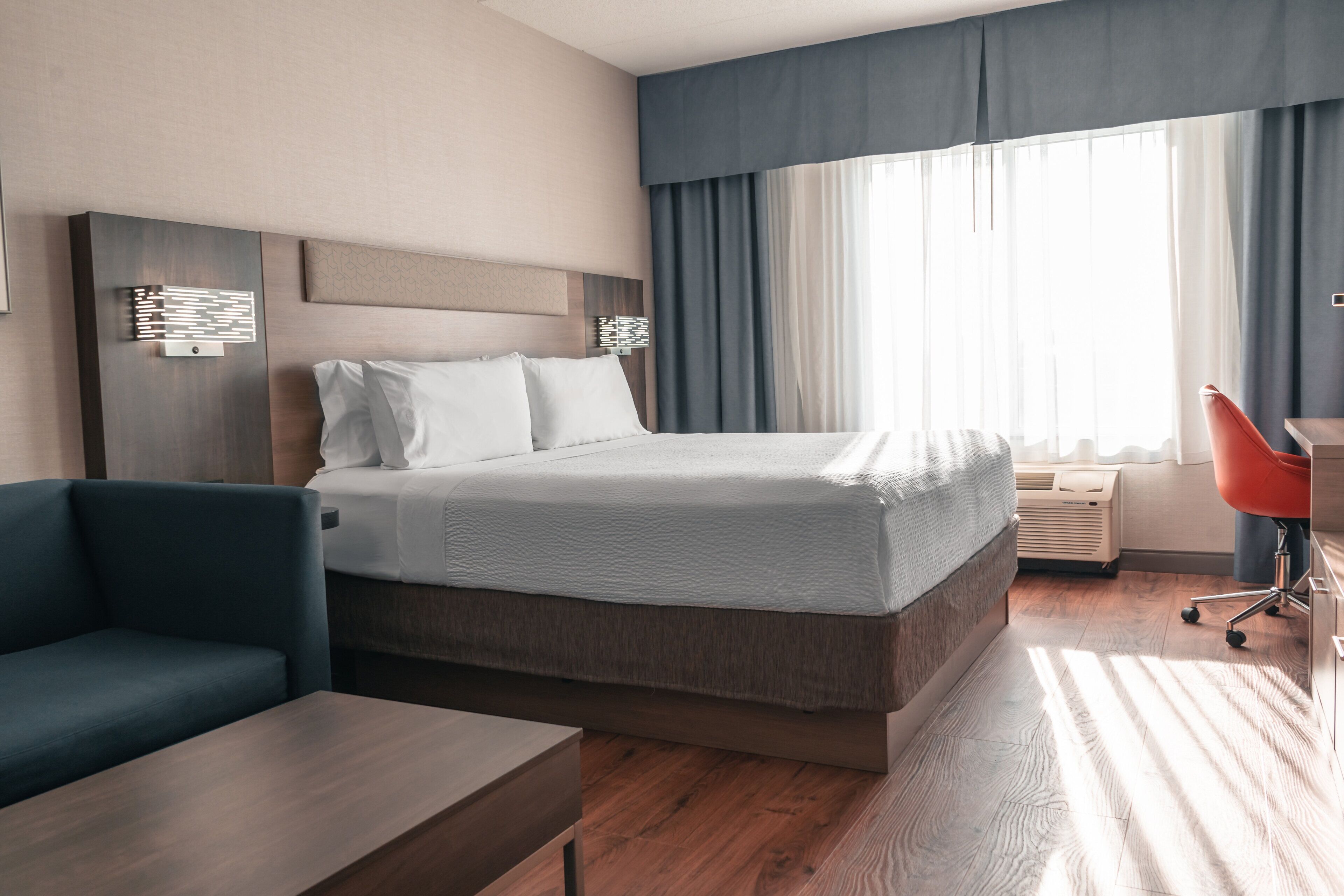 Una habitación de hotel con cama, escritorio, silla y sofá.