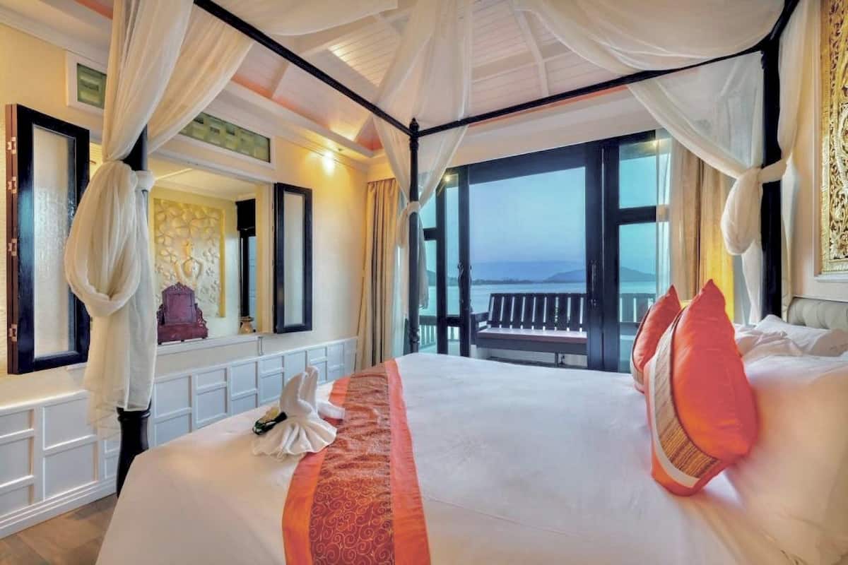 A luxurious bedroom with a large bed, a canopy, and a balcony with a view.