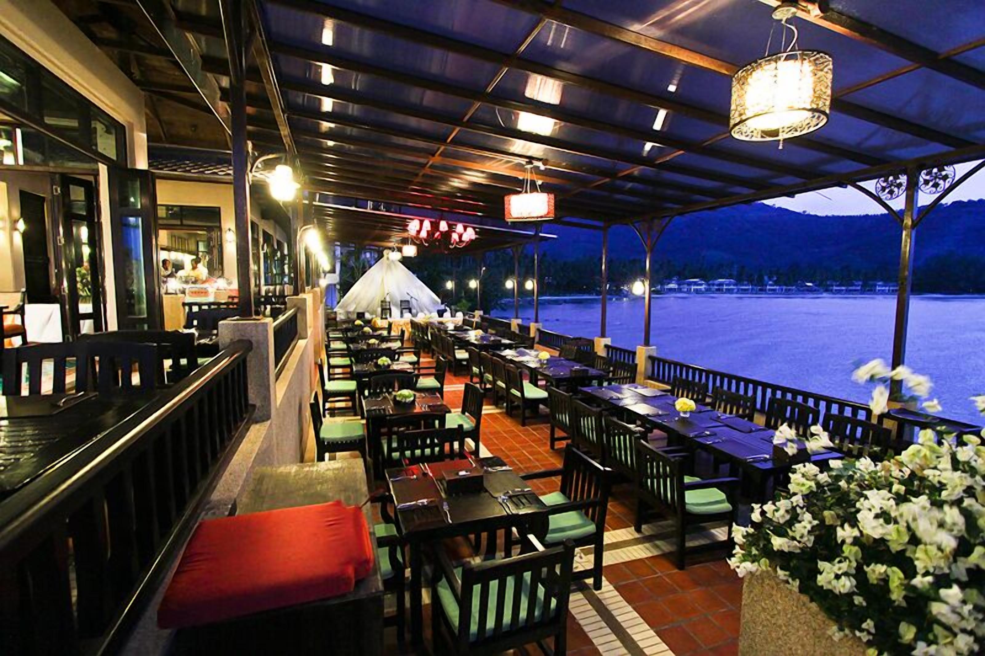 Un restaurant en plein air avec des tables et des chaises, un espace couvert et une vue sur un plan d’eau.