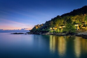 A coastal property with multiple buildings, a calm sea, and a clear sky.