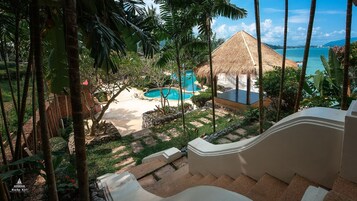 Un resort con piscina, una estructura de techo de paja y vista al mar.