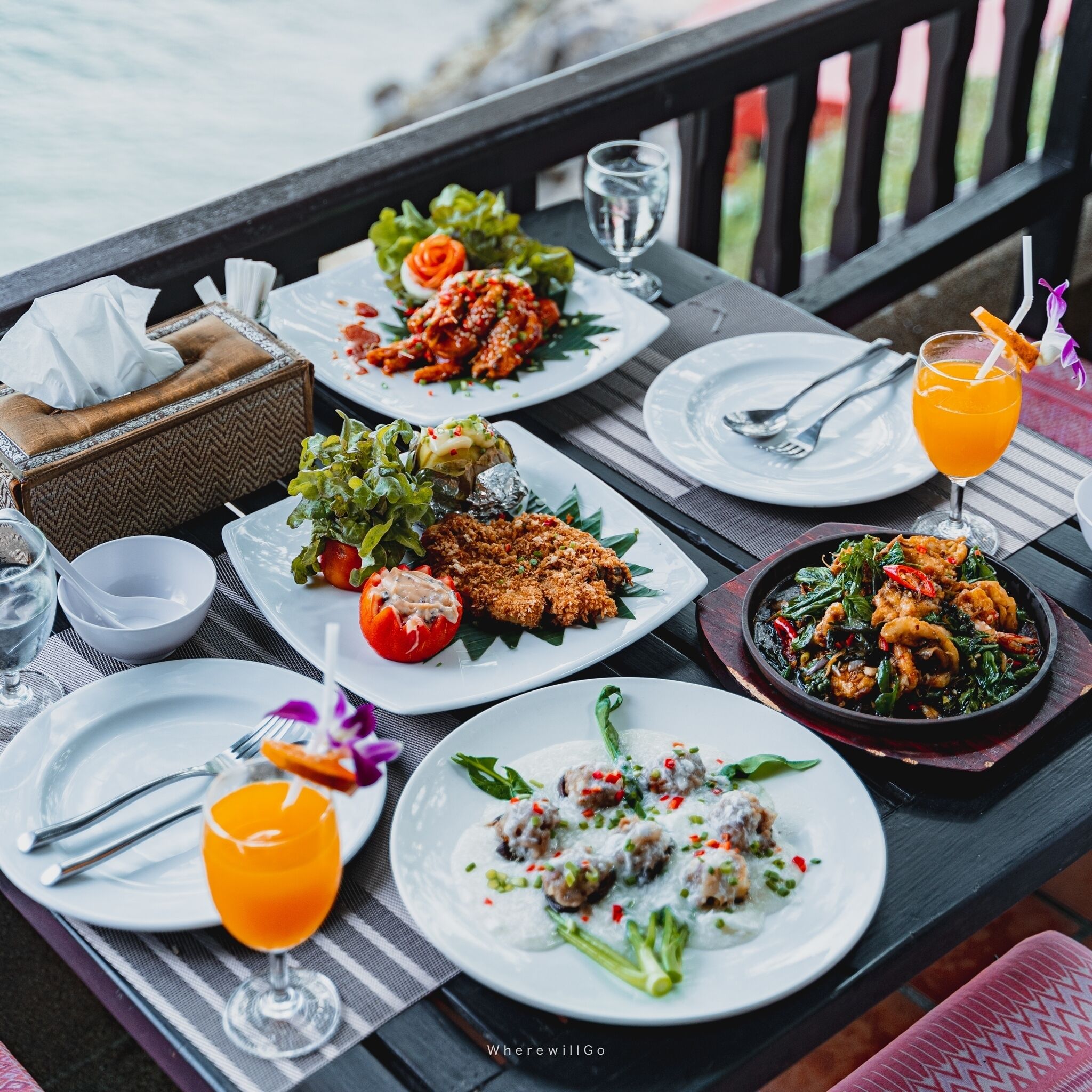 A table set with various dishes, drinks, and a tissue box.