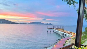 A wooden deck with a view of the sea and a pier extending into the water.